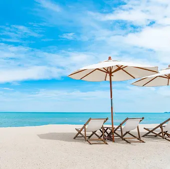 White sandy beach with two beach chairs and umbrella
